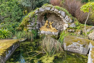 A stone grotto with a gilded statue over a spring-fed pond in the garden.