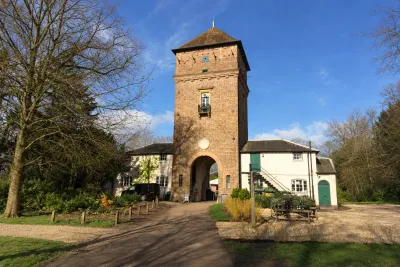 A brick water tower and gatehouse with an arch, seen across a lawn.