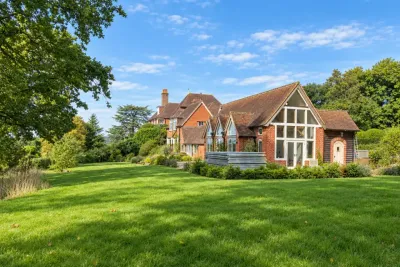 A red brick country house with tall chimneys across a wide lawn.