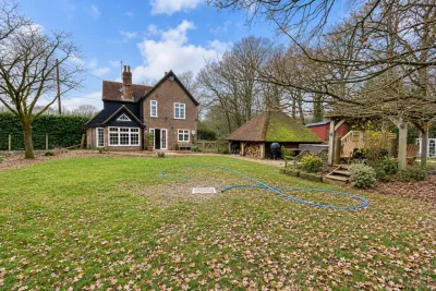 A cottage across its lawn with a blue water pipe laid out over the grass to the house.