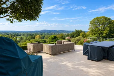 A stone terrace with covered garden furniture, looking out across the countryside.