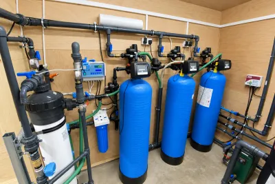 A plywood-lined plant room with the ultrafiltration unit, three blue pressure vessels and a chlorination controller.