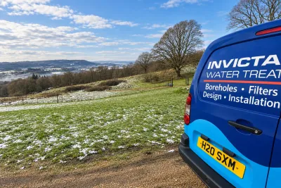 The side of an Invicta van on a hillside drive, with frost and snowdrops on the grass and hills beyond.