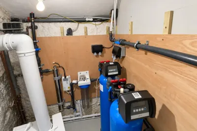 A cellar plant room with a blue pressure vessel, a water softener and a UV unit.