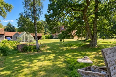 Parkland with a mature oak, a greenhouse and a farmhouse beyond, and an open chamber in the foreground.