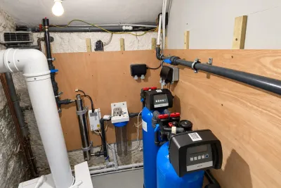 A cellar plant room with a blue pressure vessel, a water softener and a UV unit.