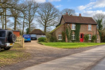 A brick and tile-hung cottage with an Invicta van on the gravel drive, under bare winter trees.
