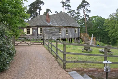 A timber lodge with a verandah beside a post-and-rail paddock and a gravel drive.